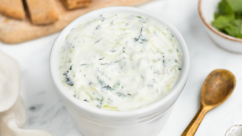 Bowl of tzatziki sauce next to small gold spoon