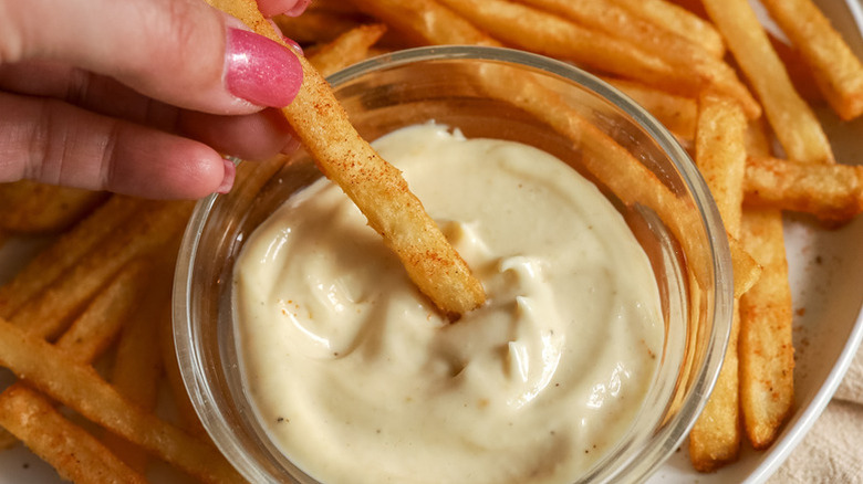 Dipping fry into small bowl of truffle aioli