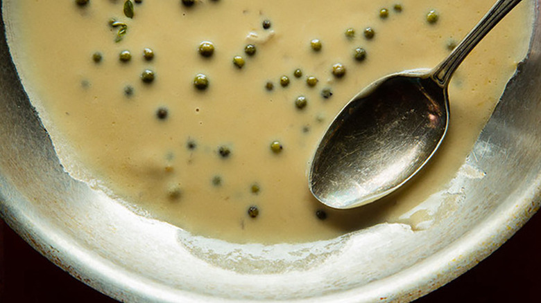 Close up of green peppercorn sauce in pan with spoon