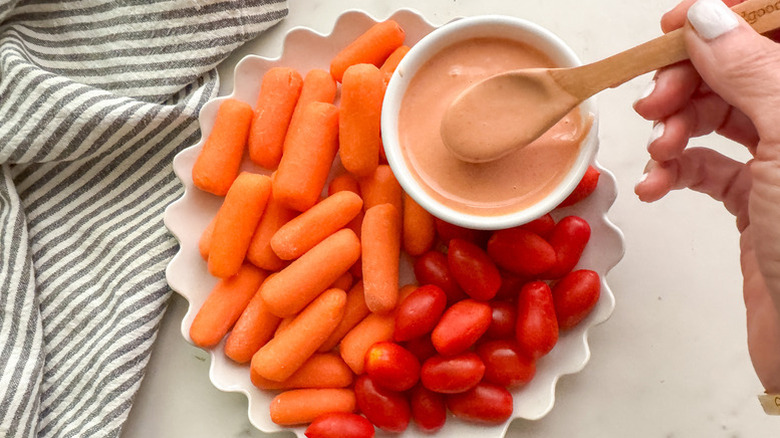Bowl of yum yum sauce on plate with grape tomatoes and baby carrots