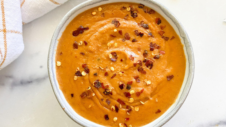 Bowl of peanut sauce topped with red pepper flakes