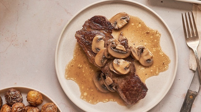 Plate of steak topped with mushroom sauce