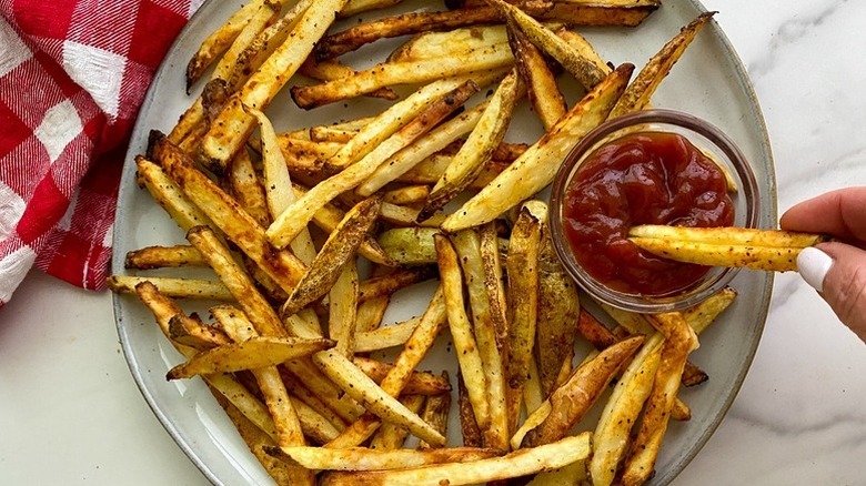 Crispy french fries on a plate with tomato ketchup