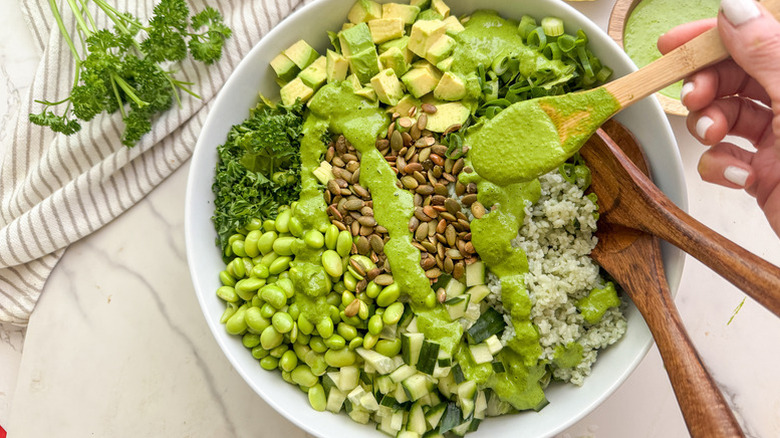 Super green grain salad in a bowl, drizzled with green dressing