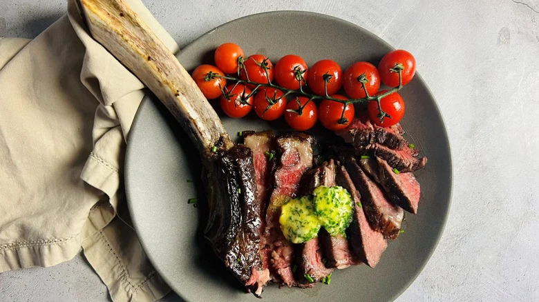 grilled tomahawk with herb butter and cherry tomatoes
