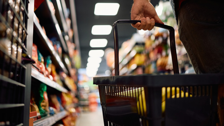 Hand holding a shopping cart in the grocery store aisle