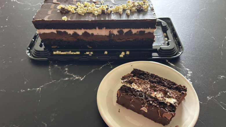 Slice of Costco tuxedo mousse cake on plate with whole cake in background