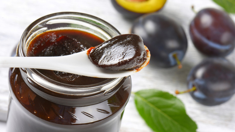 Plum jam on a spoon atop a jar