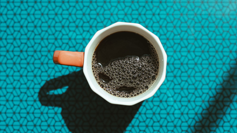 Mug of black coffee on blue table