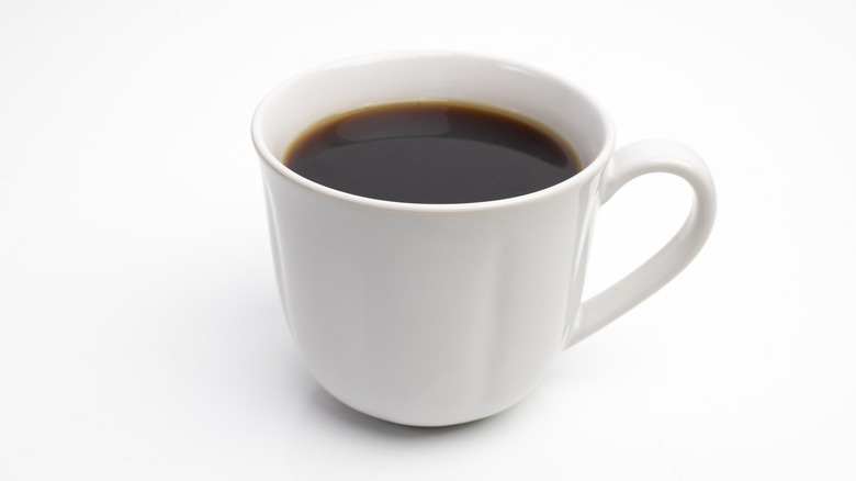 White mug of coffee on white surface