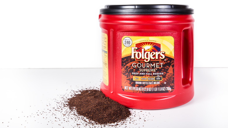 Folgers canister and ground coffee on white background