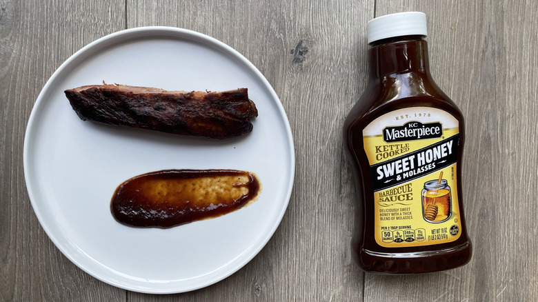 KC Masterpiece barbecue sauce bottle with ribs on a plate