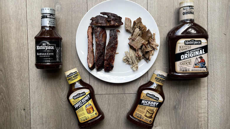 Four KC Barbecue sauces with ribs and pulled pork on a wooden surface