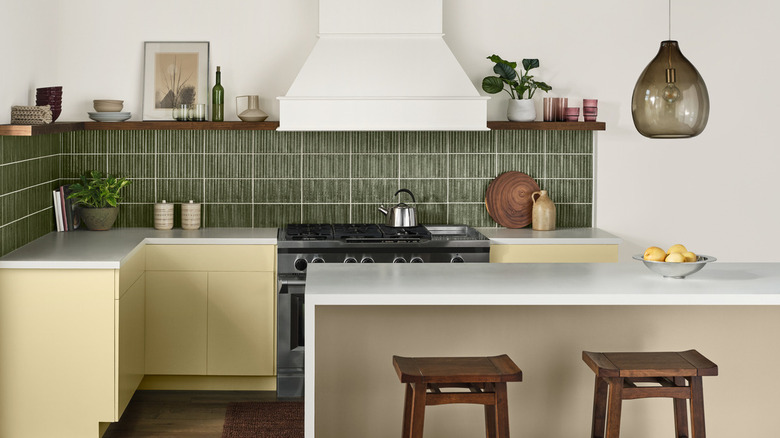 A kitchen with yellow cabinets and a green backsplash