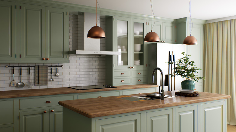 A kitchen with muted green cabinets