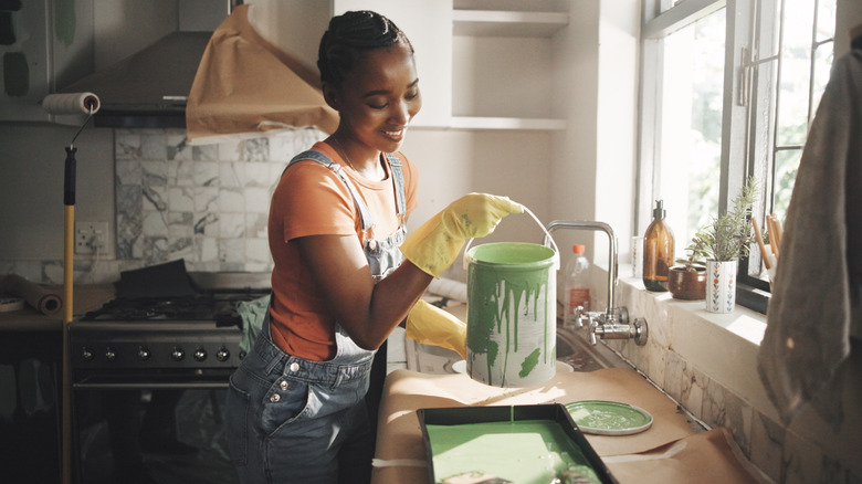 A smiling person preparing to paint a kitchen
