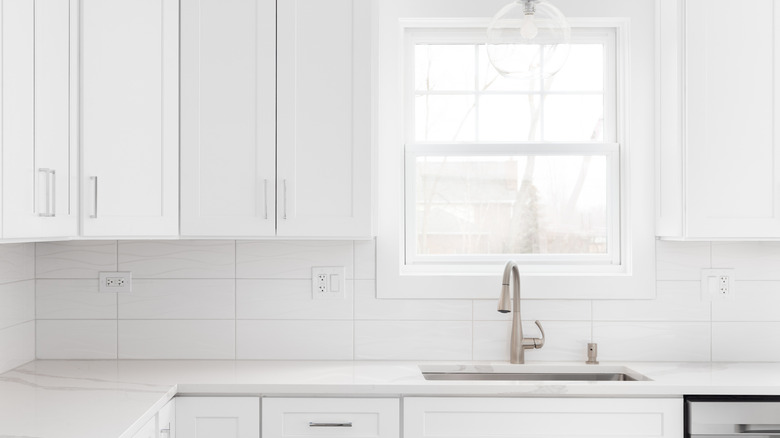 An all-white kitchen with metal furnishings