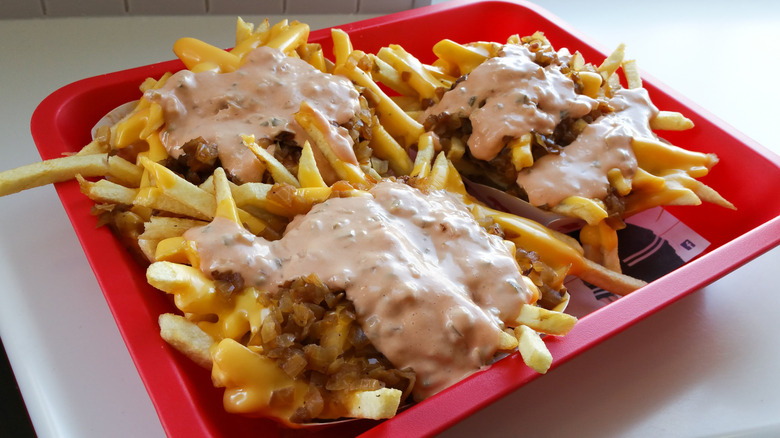 a red plastic tray filled with three orders of Animal Style fries from In-N-Out