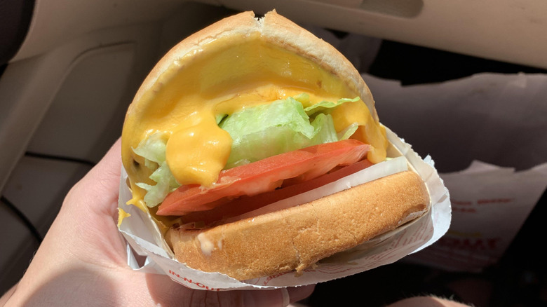 a hand holding an In-N-Out Grilled Cheese in the car
