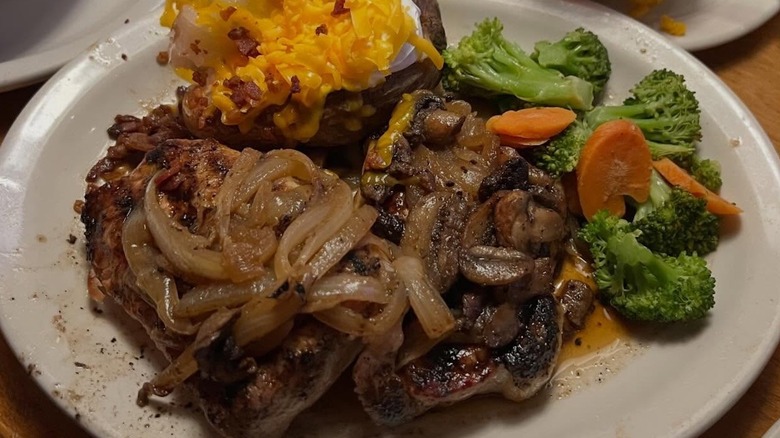 Closeup of a steak smothered in grilled onions and mushrooms at Texas Roadhouse