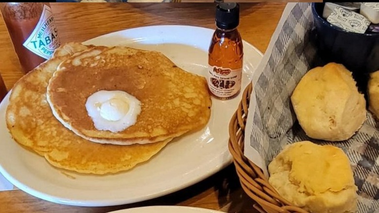 A plate of pancakes beside a basket of biscuits
