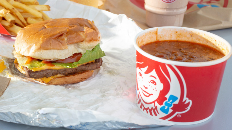 Cup of Wendy's chili sits near a cheeseburger
