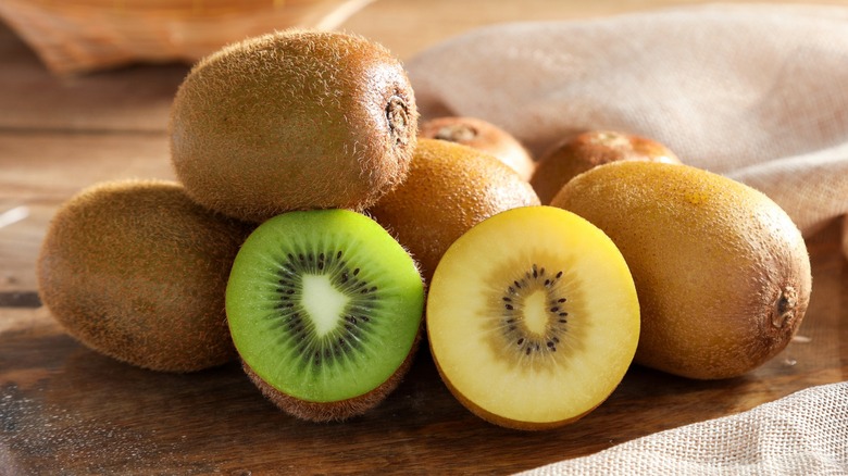 A stack of whole and sliced green and gold kiwis