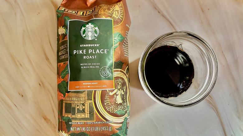 Top-down shot of Starbucks Pike Place bag next to mason jar of cold black coffee