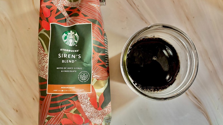 Top-down shot of Starbucks Siren's Blend bag next to mason jar of cold black coffee