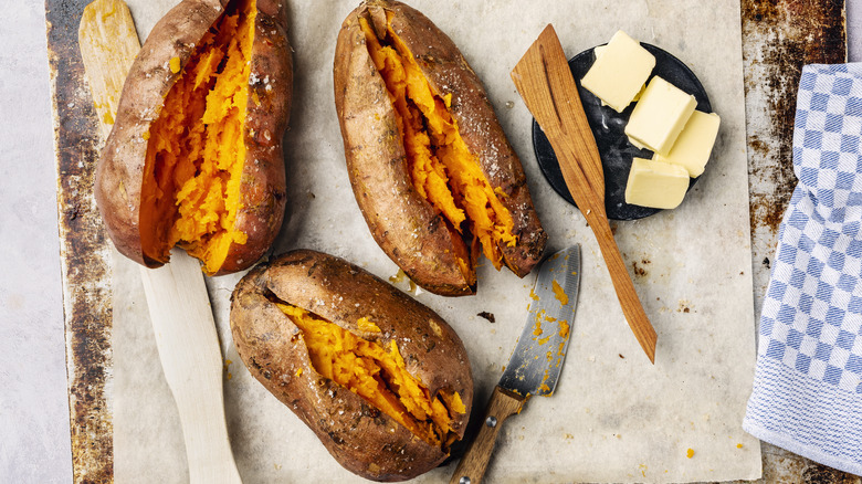 Three baked sweet potatoes with slices of butter.