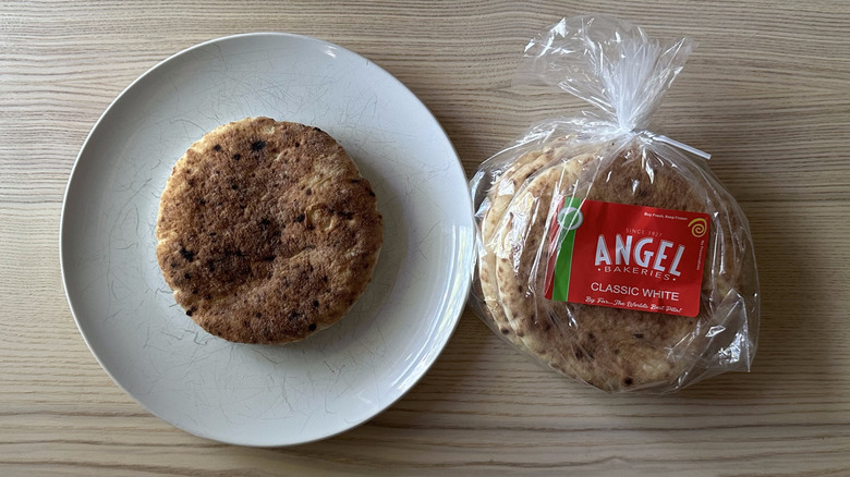 A pack of Angel Bakeries Pita Bread on wooden table with one pita displayed on white plate