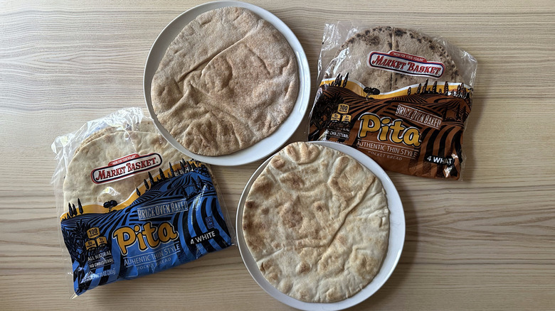 Two packs of Market Basket Pita Bread on wooden table with two breads on plates