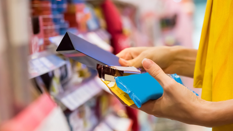 person holding chocolate bars in store