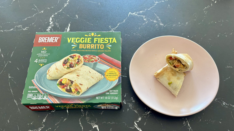 Aldi veggie burrito box next to halved burrito on plate