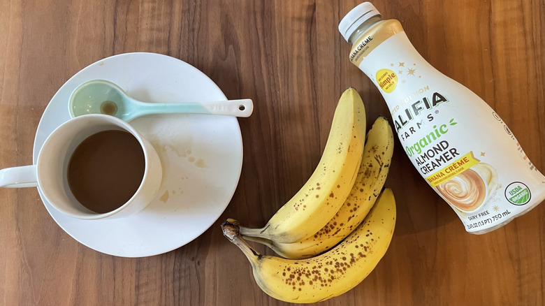 Bananas, a coffee cup, spoon, and Califia Farms creamer
