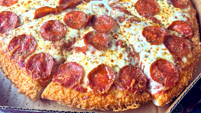 Top down view of a pepperoni pizza with the Crispy Parm crust from Pizza Hut. The edges are covered in Golden crispy shreds of Parmesan cheese