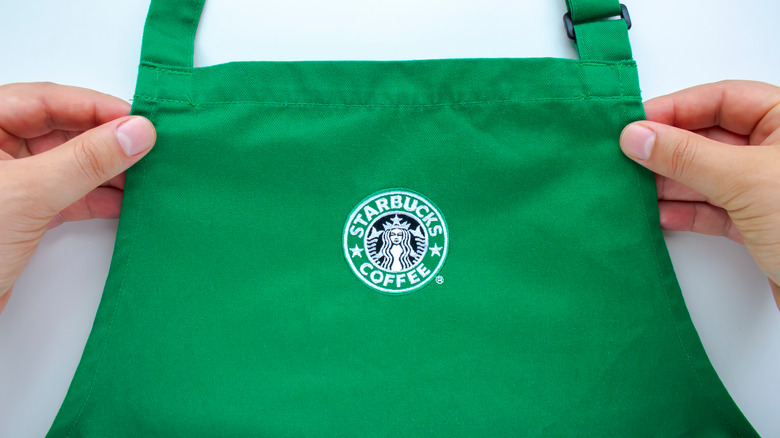 Hands holding a green Starbucks-branded apron