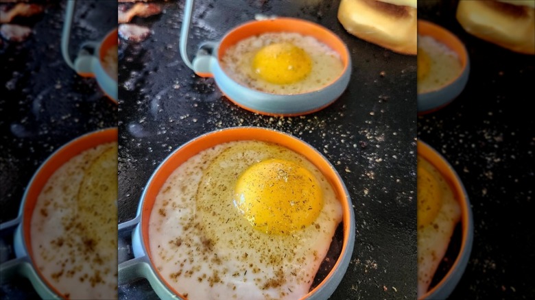 Two Blackstone egg molds being used to make fried eggs on a Blackstone griddle