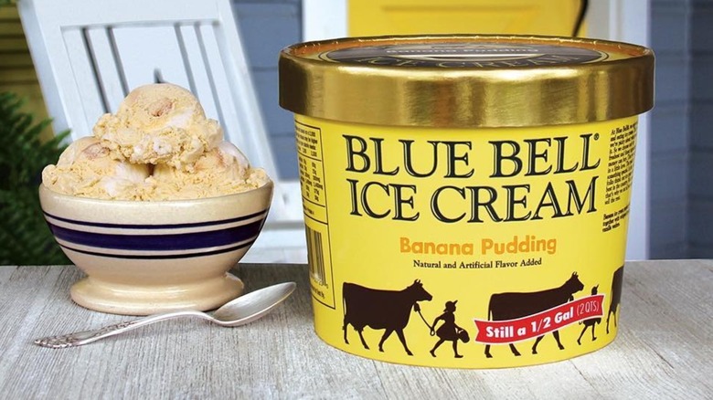 A carton of Blue Bell Banana Pudding ice cream on an outdoor table next to a bowl of ice cream