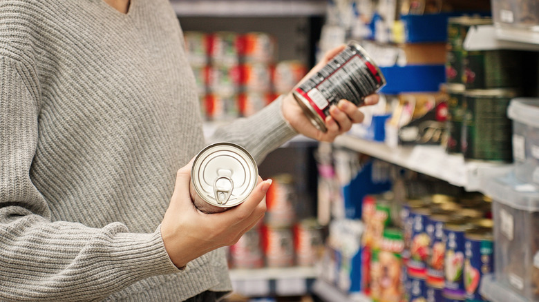 Woman comparing two canned food products in grocery store