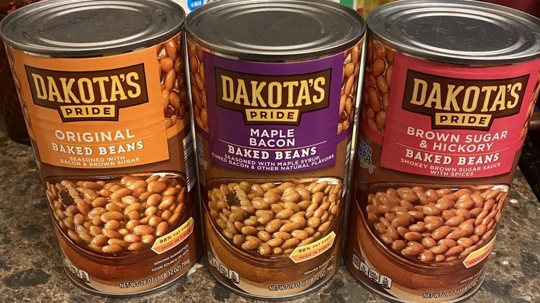 Three cans of baked beans in varying flavors side by side on countertop