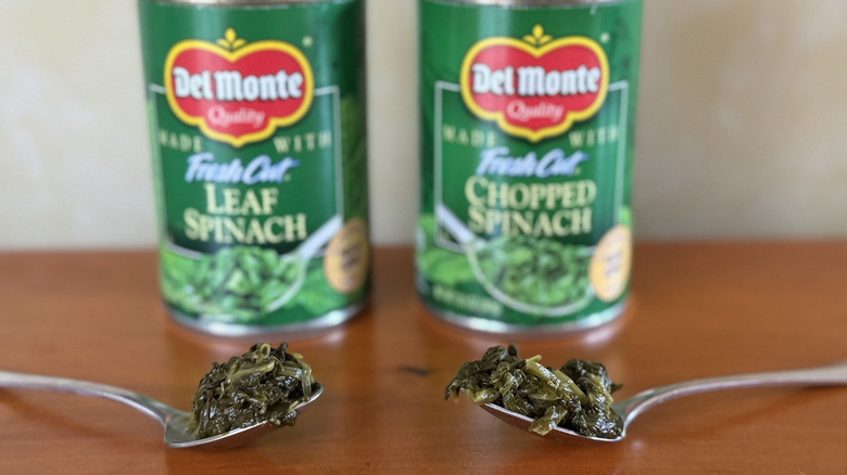 Two spoonfuls of spinach in front of two Delmonte cans