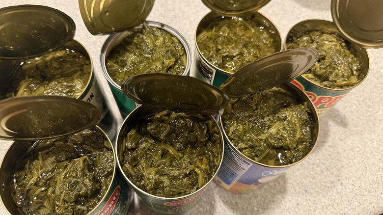 Overhead shot of seven open cans of spinach