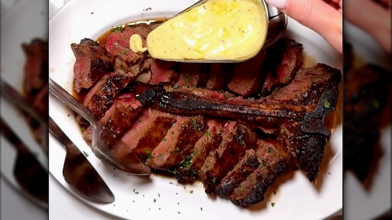 Sliced dry-age porterhouse with bone on white plate at Morton's the Steakhouse