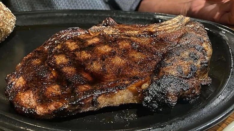 Grilled bone-in ribeye on black plate from Outback Steakhouse