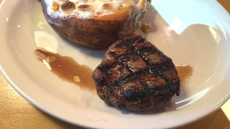Grilled filet mignon with sweet potato on white plate at Texas Roadhouse