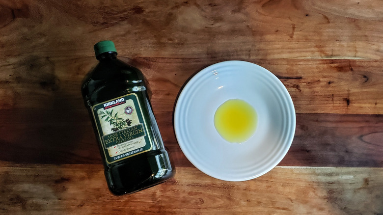 Bottle of Italian extra virgin olive oil and some oil poured on a white plate.