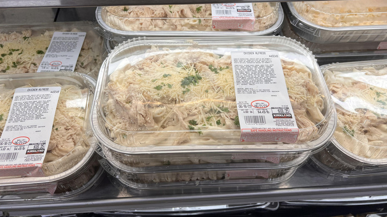 Containers of Kirkland Signature Chicken Alfredo with Penne Pasta on display in the deli case of a Costco warehouse