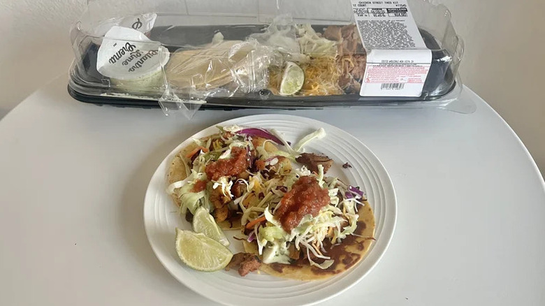 A package of Kirkland Signature Chicken Street Tacos on a kitchen table and a white plate of prepared tacos in the foreground