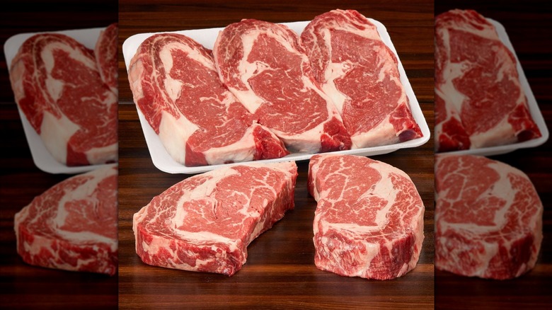 A beauty shot of five Kirkland Signature USDA Prime ribeye steaks in a Styrofoam container and on a wooden table.
